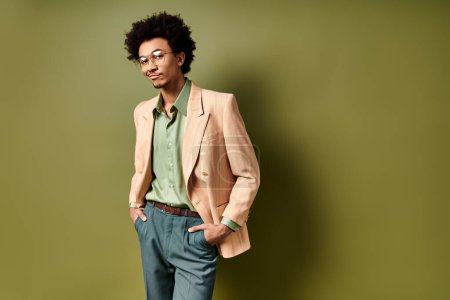 A young African American man, stylishly dressed, stands confidently in front of a vibrant green wall, wearing trendy sunglasses.