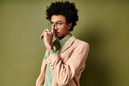 Foto de Joven hombre afroamericano con estilo en traje de moda y gafas sobre un fondo verde. - Imagen libre de derechos