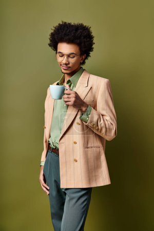 Foto de Elegante joven afroamericano con traje y gafas de sol, sosteniendo una taza de café sobre un fondo verde vibrante. - Imagen libre de derechos