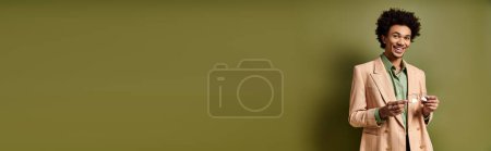 Téléchargez les photos : Jeune homme afro-américain élégant en costume et lunettes de soleil debout avec confiance à côté d'un mur vert vif. - en image libre de droit