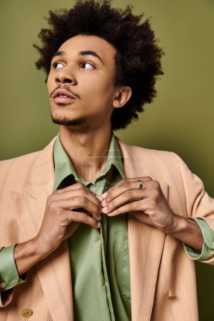 Stylish young African American man with curly hair wearing a green shirt on a green background.