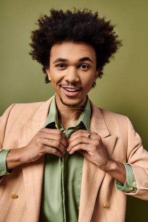 Stylish young African American man in a suit buttoning shirt against a trendy green background.