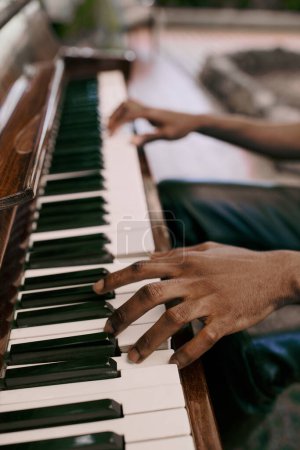 Téléchargez les photos : Homme afro-américain élégant joue du piano avec les mains dans un cadre de jardin luxuriant. - en image libre de droit