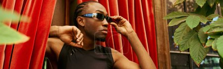 Foto de Un hombre afroamericano con estilo en una camisa negra y gafas de sol. - Imagen libre de derechos