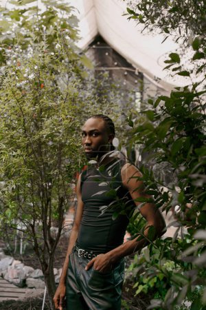 A sophisticated African American man stands in the heart of a lush forest.