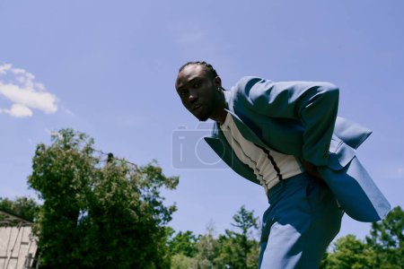 Photo for African American man in blue suit posing actively outdoors. - Royalty Free Image