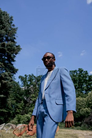 Foto de Hombre guapo en traje azul posa en jardín verde vivo. - Imagen libre de derechos