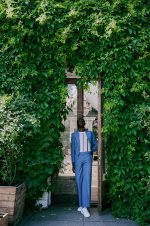 Un hombre afroamericano sofisticado con un traje azul camina confiadamente hacia una puerta.