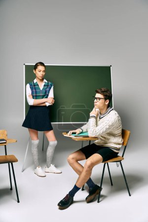 Handsome man and beautiful woman sitting in front of chalkboard at college.