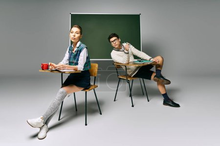 Two stylish students engaged in study at a desk before a green board.