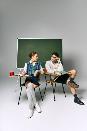 Élégant homme et femme assis près d'un tableau vert dans un cadre universitaire.