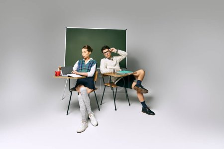 Elegantes estudiantes masculinos y femeninos sentados frente a un tablero verde en un entorno universitario.