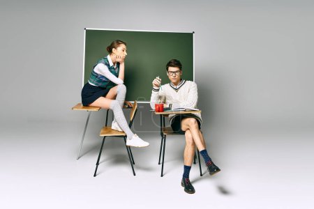 Schöner Mann und stilvolle Frau sitzen vor einer Tafel in einem College-Setting.