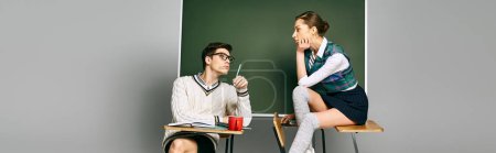 Photo for Elegant male and female students sitting in front of a green chalkboard in college. - Royalty Free Image