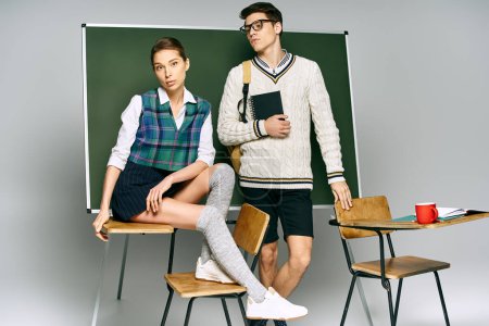 Ein stilvoller Mann und eine stilvolle Frau posieren vor einem grünen Brett in einem College-Setting.