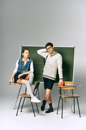 Ein gut aussehender Mann und eine gut aussehende Frau posieren elegant vor einem grünen Brett in einem College-Setting.