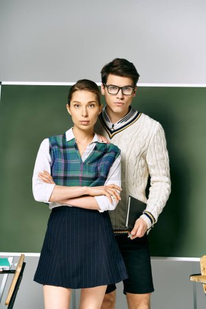 Elegant man and woman students standing in front of a green board in college.