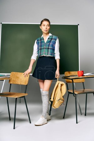 Photo for A woman in a plaid skirt stands by a green board. - Royalty Free Image