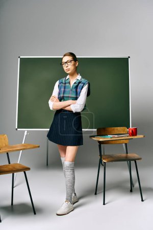 Female student in school uniform standing before a green board at college.