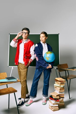 students in college attire standing by green board with books and globe.