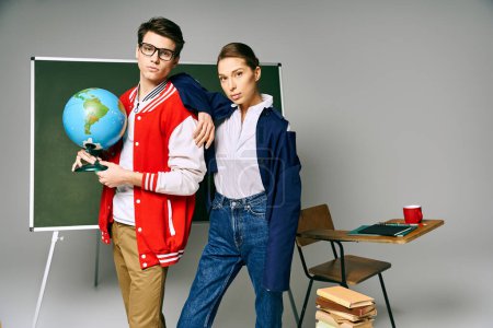 A male and female students stand in front of a chalkboard in a college classroom.