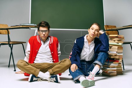 Zwei stylische Studenten sitzen neben einem grünen Brett in einem College-Klassenzimmer.
