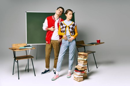 Téléchargez les photos : Un élégant mâle et femelle étudiants frappent une pose devant un tableau vert dans une salle de classe d'université. - en image libre de droit