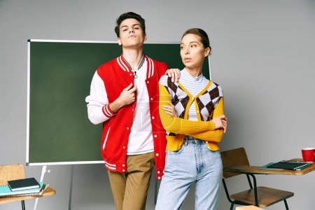 Two young people in casual attire stand confidently in front of a chalkboard in a college classroom.