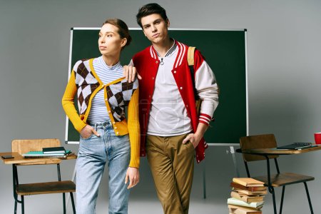 Photo for A male and female students in casual clothing posing in front of a green board in a college classroom. - Royalty Free Image