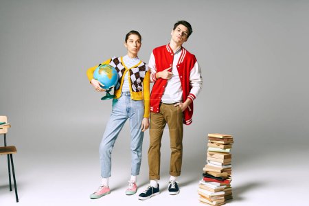 Two young students posing in front of a tall stack of books in a classroom setting.