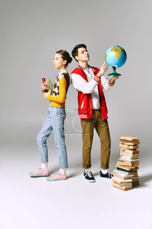 A man and a woman stand beside a tall stack of books in a college classroom.