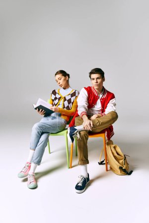 Young male and female students in stylish outfits sitting on colorful chairs, casually posing.
