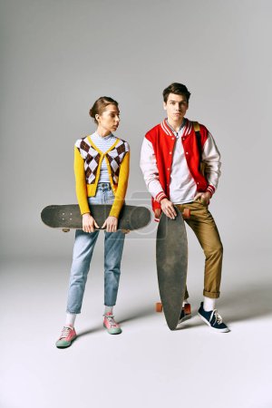 Zwei stylische junge Erwachsene halten Skateboards vor weißer Kulisse.