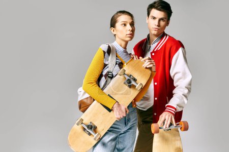 Photo for Young male and female students proudly hold skateboards in a college setting. - Royalty Free Image