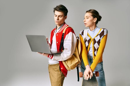 Téléchargez les photos : Jeunes étudiants masculins et féminins debout avec un ordinateur portable dans une salle de classe du collège. - en image libre de droit