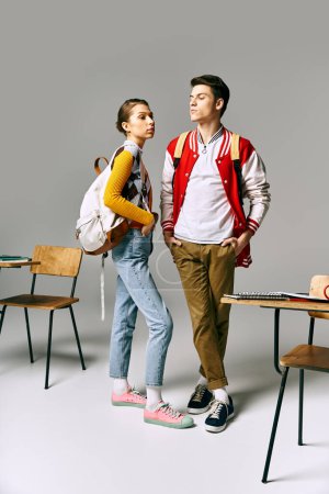 A male and female students in casual attire pose in a classroom setting.