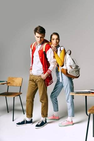 Photo for Attractive male and female students standing in front of a desk in a college classroom. - Royalty Free Image