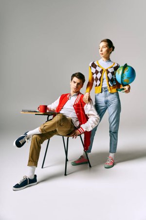 Téléchargez les photos : Un homme et une femme en tenue décontractée posent gracieusement sur une chaise dans une salle de classe du collège. - en image libre de droit