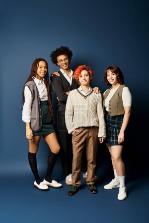 Foto de Jóvenes amigos multiculturales, incluida una persona no binaria, se unen con un atuendo elegante sobre un fondo azul oscuro. - Imagen libre de derechos