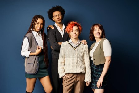 Foto de A group of young multicultural friends, including a nonbinary person, standing together in stylish attire on a dark blue background. - Imagen libre de derechos