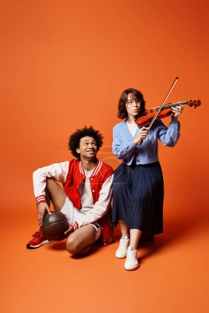 A young multicultural couple creating harmonious tunes as they play the violin together in stylish attire.