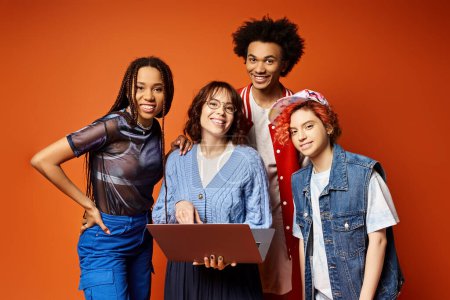 Foto de Un grupo diverso de mujeres jóvenes, incluyendo una persona no binaria, de pie con confianza junto con el ordenador portátil en un ambiente elegante estudio. - Imagen libre de derechos