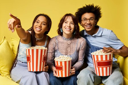 Three friends enjoy a movie night on a cozy couch, holding popcorn buckets in their hands.
