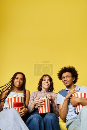 Photo for A diverse group of young friends in stylish attire are sitting closely together on a couch, enjoying each others company. - Royalty Free Image