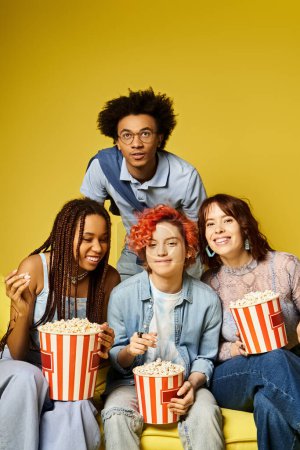 Téléchargez les photos : A diverse group of young friends sit closely, holding popcorn as they enjoy each others company in a stylish studio setting. - en image libre de droit