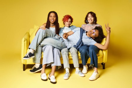 Junge multikulturelle Freunde, darunter eine nicht binäre Person, sitzen gemütlich auf einer leuchtend gelben Couch in einem stilvollen Studio-Ambiente.