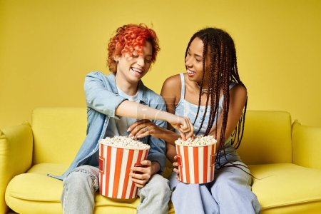 Photo for Stylish young friends lounging on a vibrant yellow couch together, showcasing diversity and friendship. - Royalty Free Image