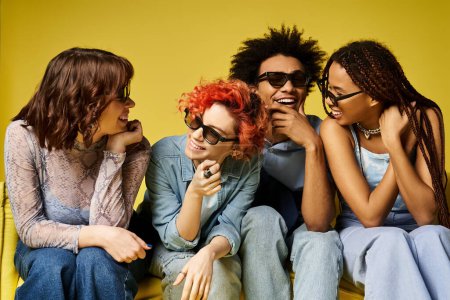 Foto de Un grupo de jóvenes amigos multiculturales, incluyendo una persona no binaria, sentados juntos con un atuendo elegante en un entorno de estudio. - Imagen libre de derechos