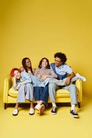 Téléchargez les photos : Un groupe diversifié d'amis, y compris un individu non binaire, assis avec désinvolture sur un canapé jaune vif dans un cadre élégant studio. - en image libre de droit