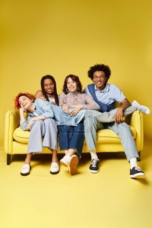 Foto de Un grupo diverso de jóvenes amigos con trajes elegantes descansando y charlando casualmente en un vibrante sofá amarillo en un entorno de estudio. - Imagen libre de derechos